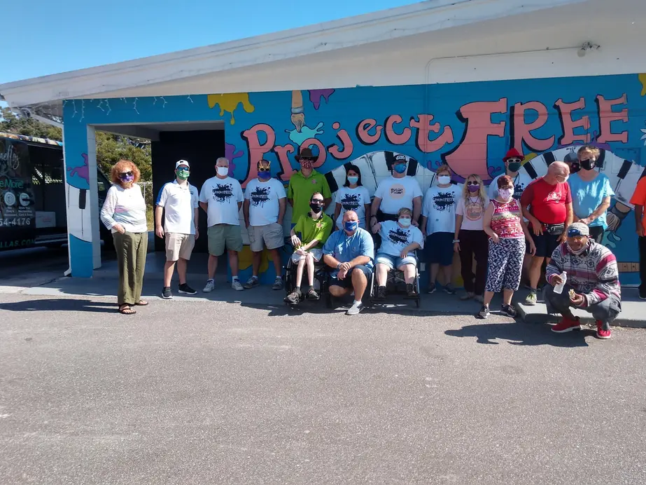 ProjectFREE members, families and staff gathered in front of the painted Project FREE mural